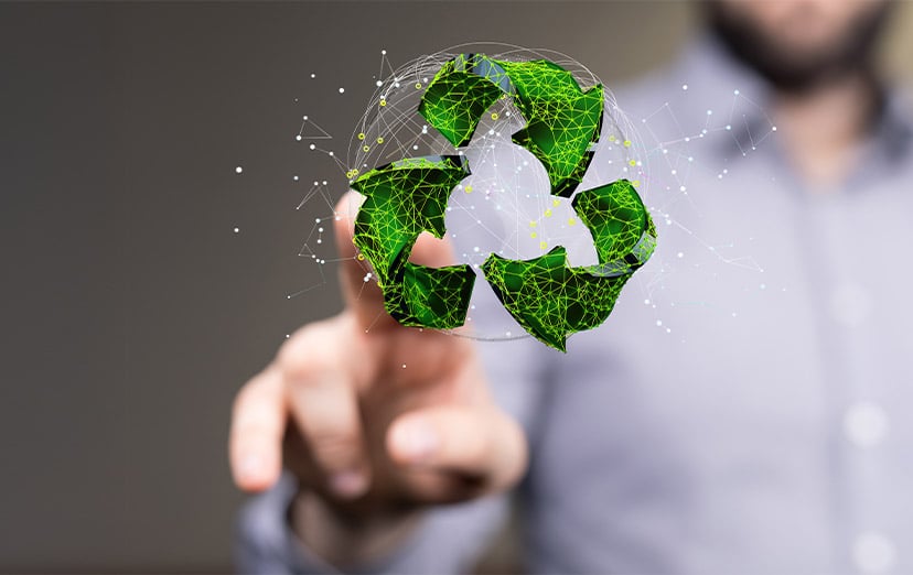 Green low-poly recycling symbol floating above a pointing finger, a person blurred behind