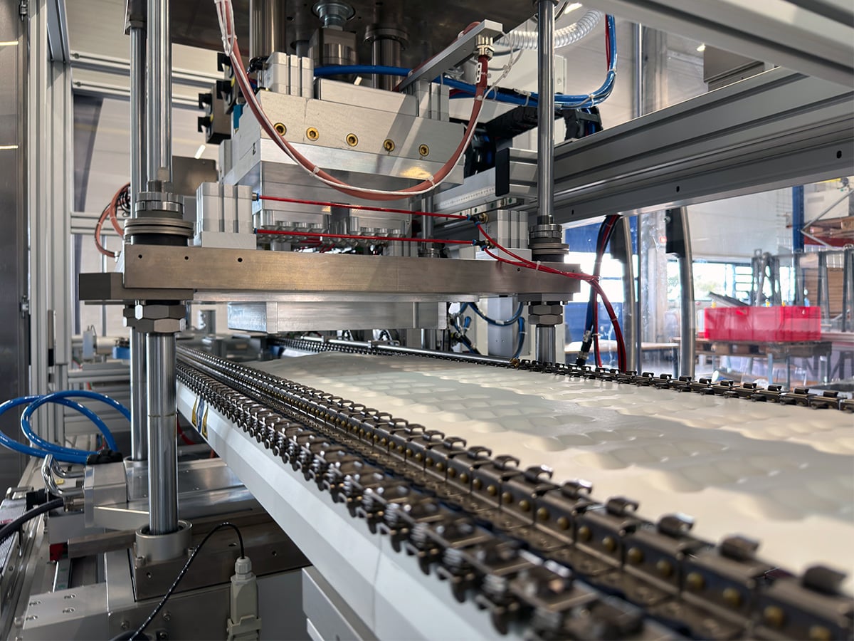 Packaging process technology: formed film with rows of cavities on chain rails under a tool head