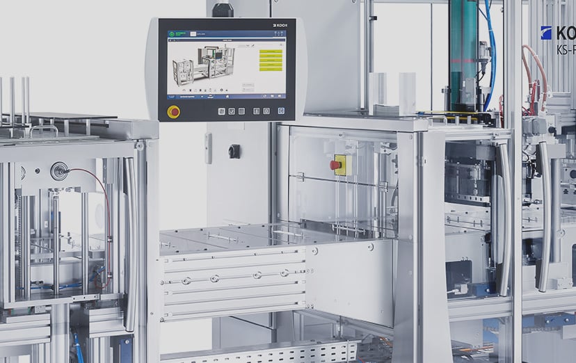 Close-up of a KOCH packaging machine with touchscreen, emergency stop and open sealing area