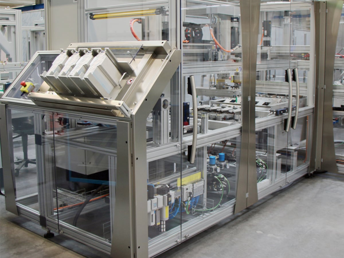 Custom-built packaging machine with glazed enclosures and a tilted feed magazine in a production environment