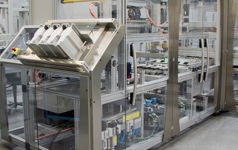 Custom-built packaging machine with glazed enclosures and a tilted feed magazine in a production environment