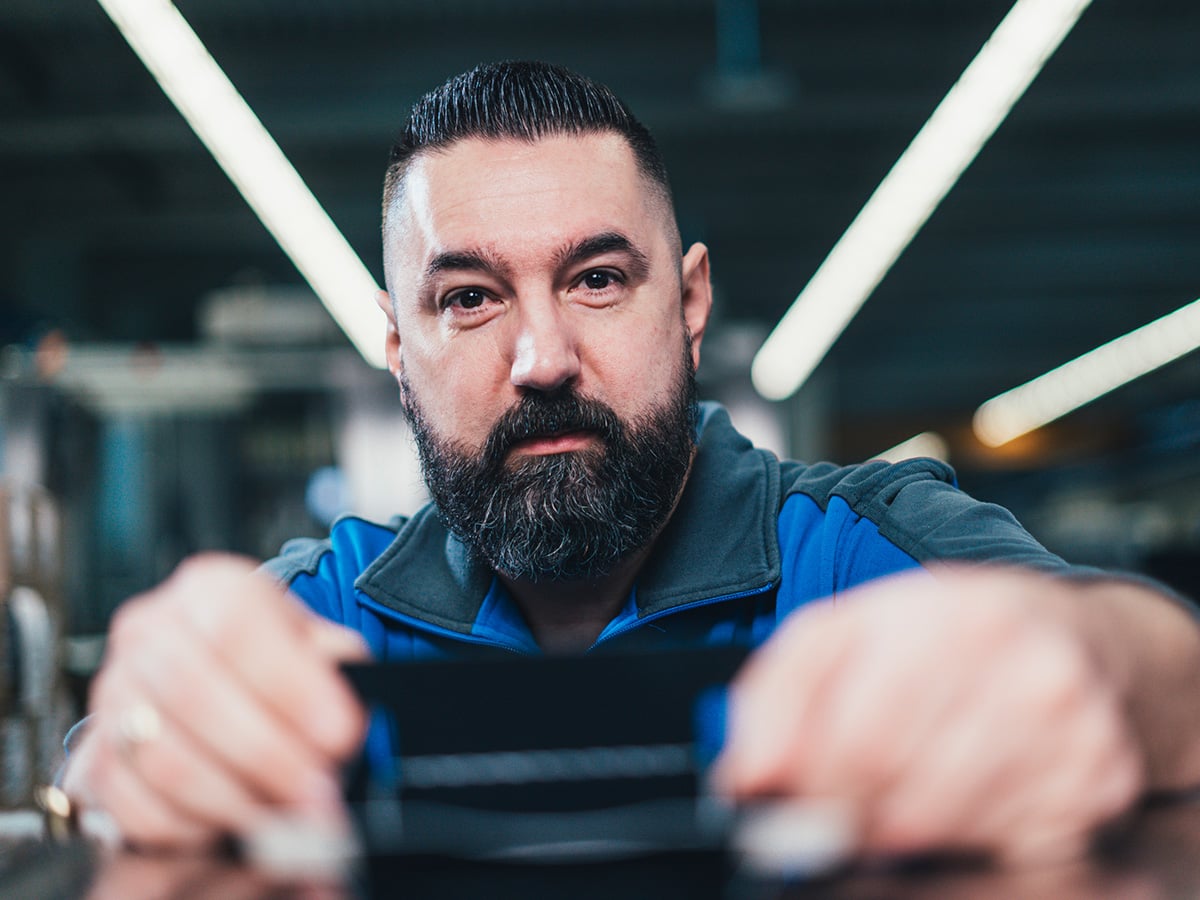 KOCH field service technician leaning over a machine component, looking directly into the camera