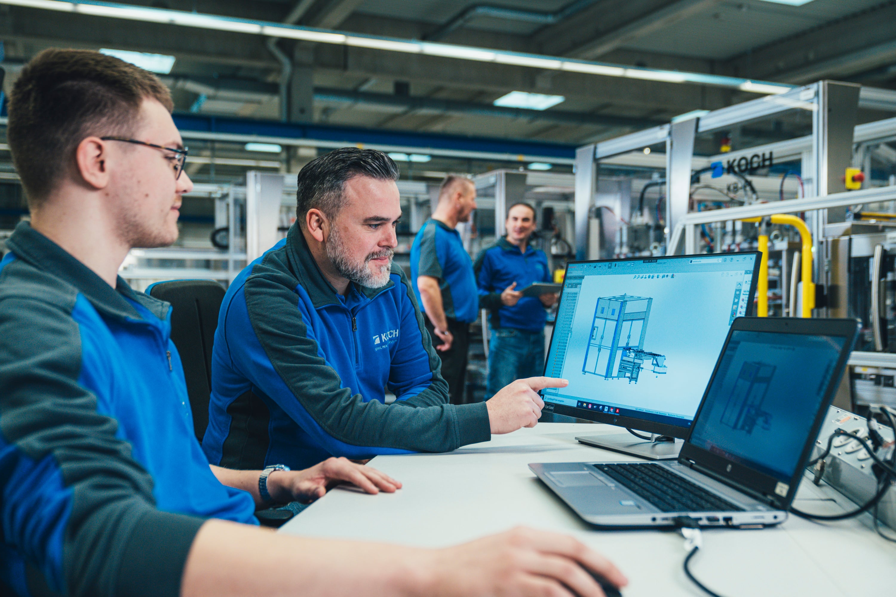 KOCH employees reviewing a machine drawing on a laptop during production support