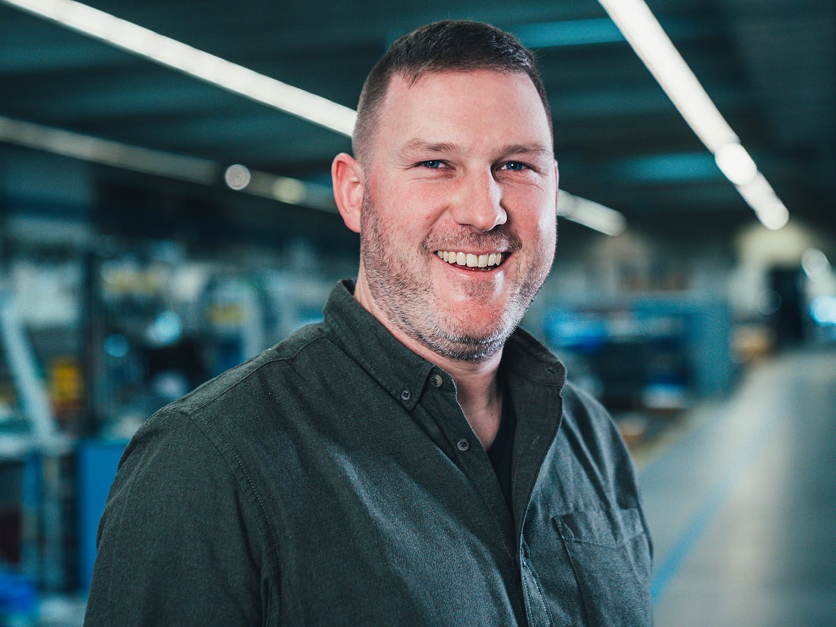 KOCH service consultant smiling at the camera in a production hall