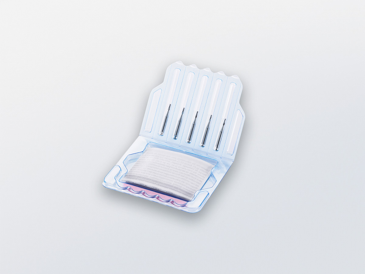 Opened folding blister holding five slim rotary dental instruments and a folded printed leaflet