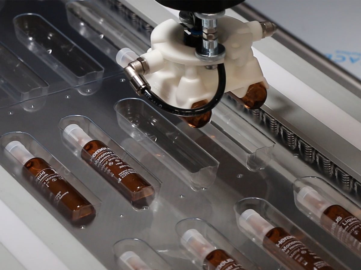 Machine head placing brown glass ampoules into the cavities of a transparent blister sheet