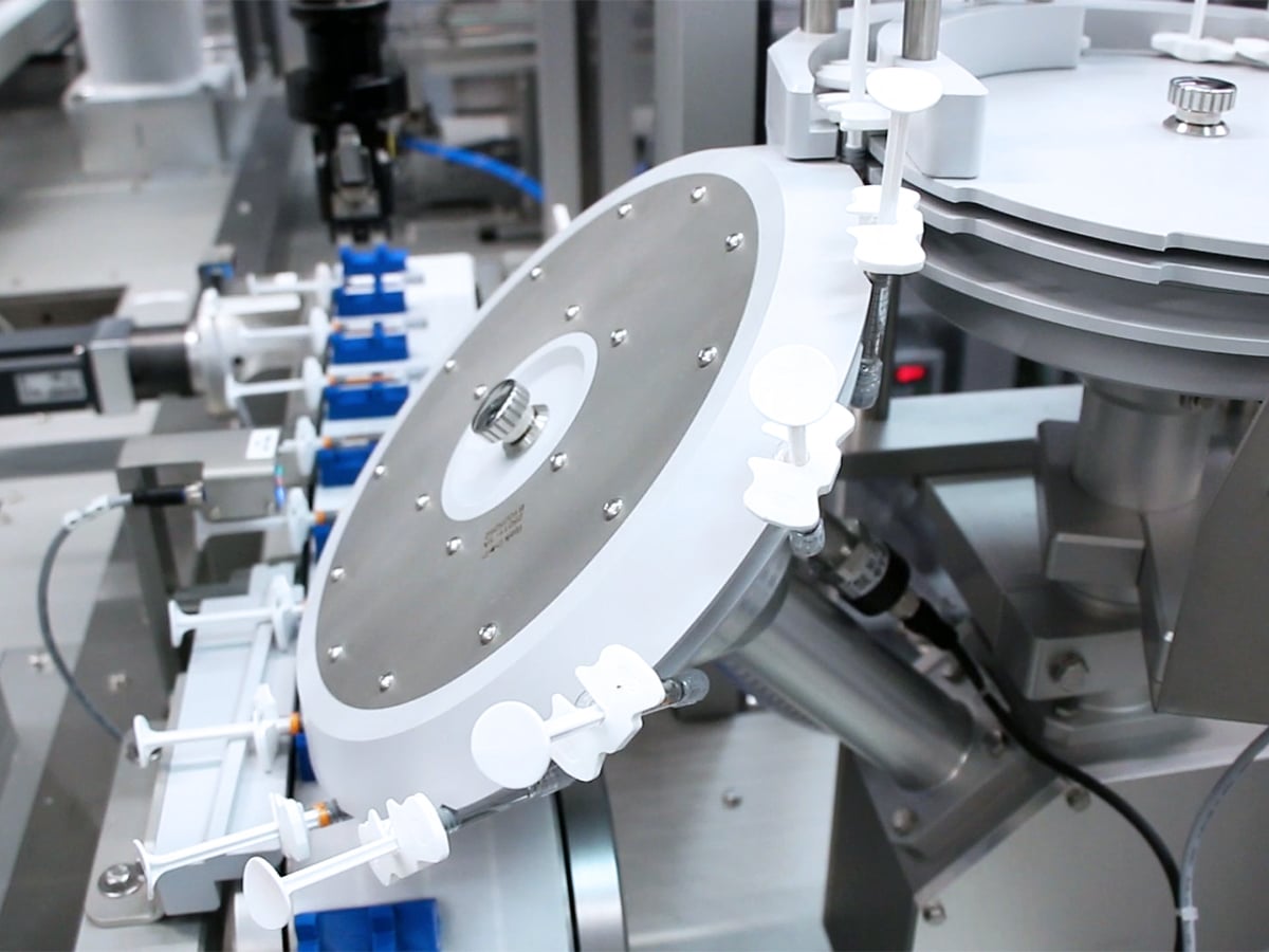 Spritzenumlegung mit rotierenden Führungselementen innerhalb der automatisierten Verpackungslinie