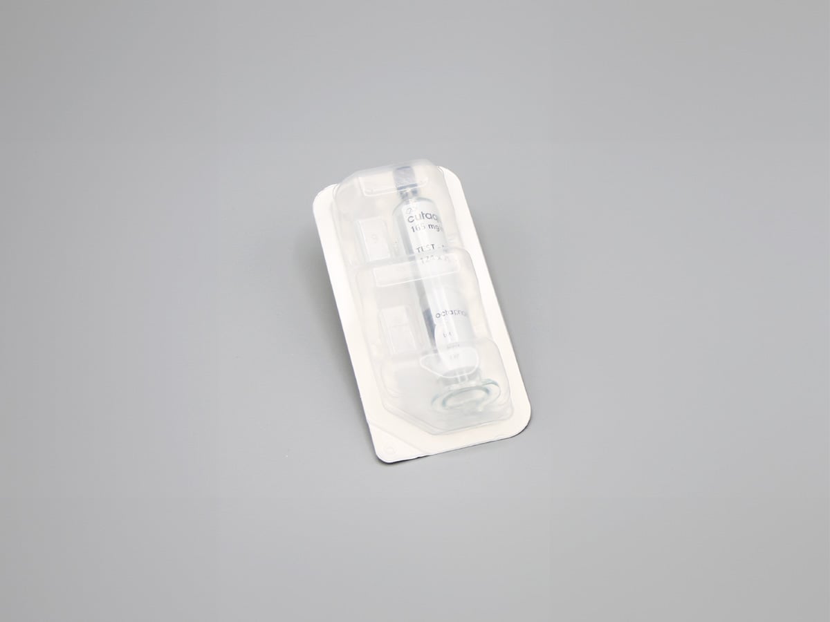 Sealed blister with a white rim holding a prefilled syringe under transparent film