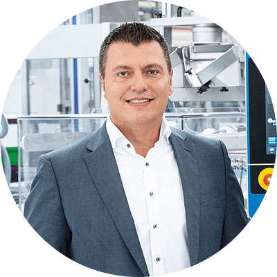 Portrait of Cristian Reiter, CTO and Managing Director at Uhlmann, in front of a packaging machine