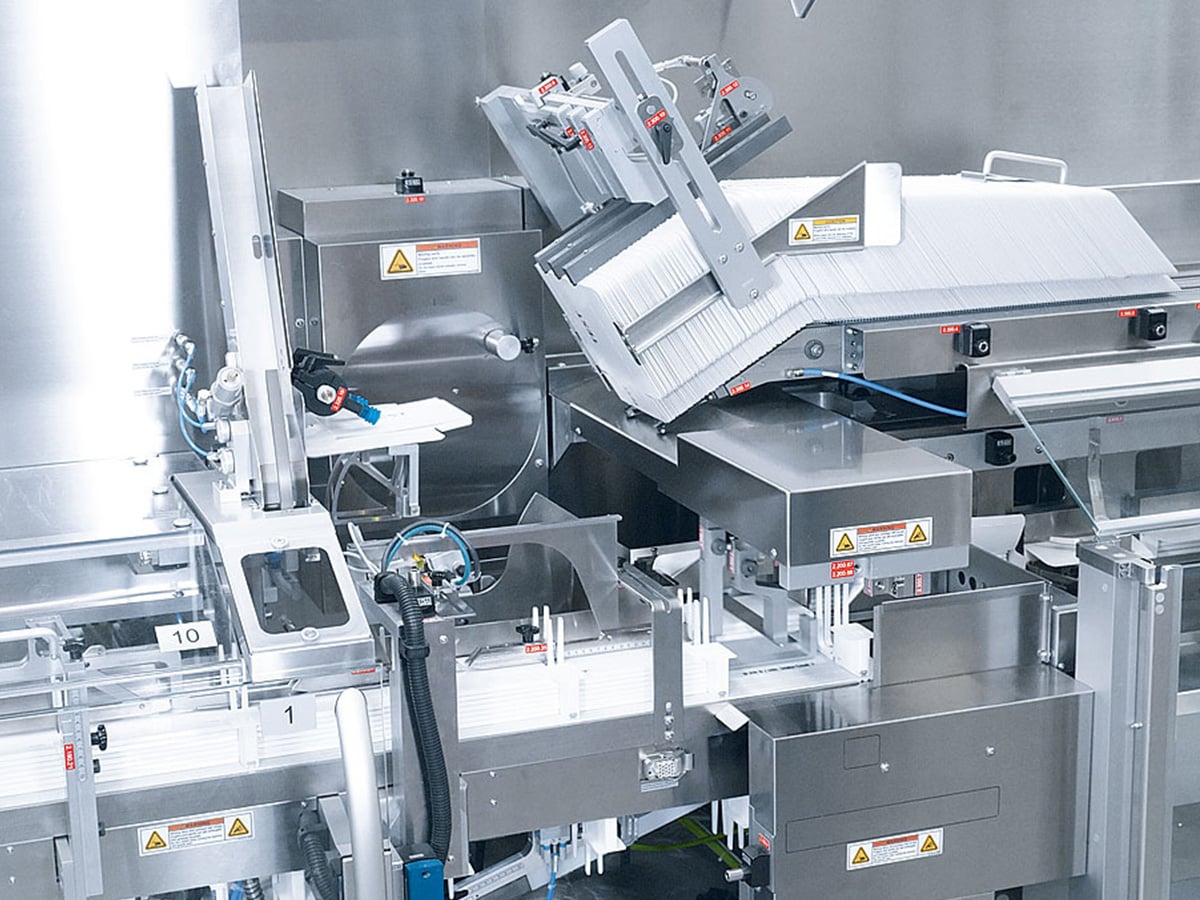 Transfer station between two machines with a stacked wallet magazine and stainless steel assemblies
