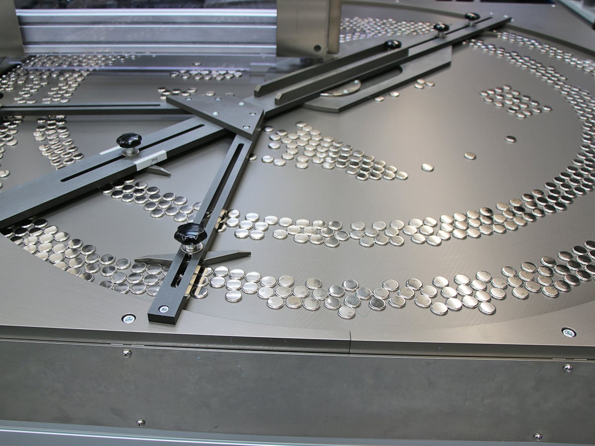 Overhead view of a sorting bowl with hundreds of button cells spiralling outward for alignment