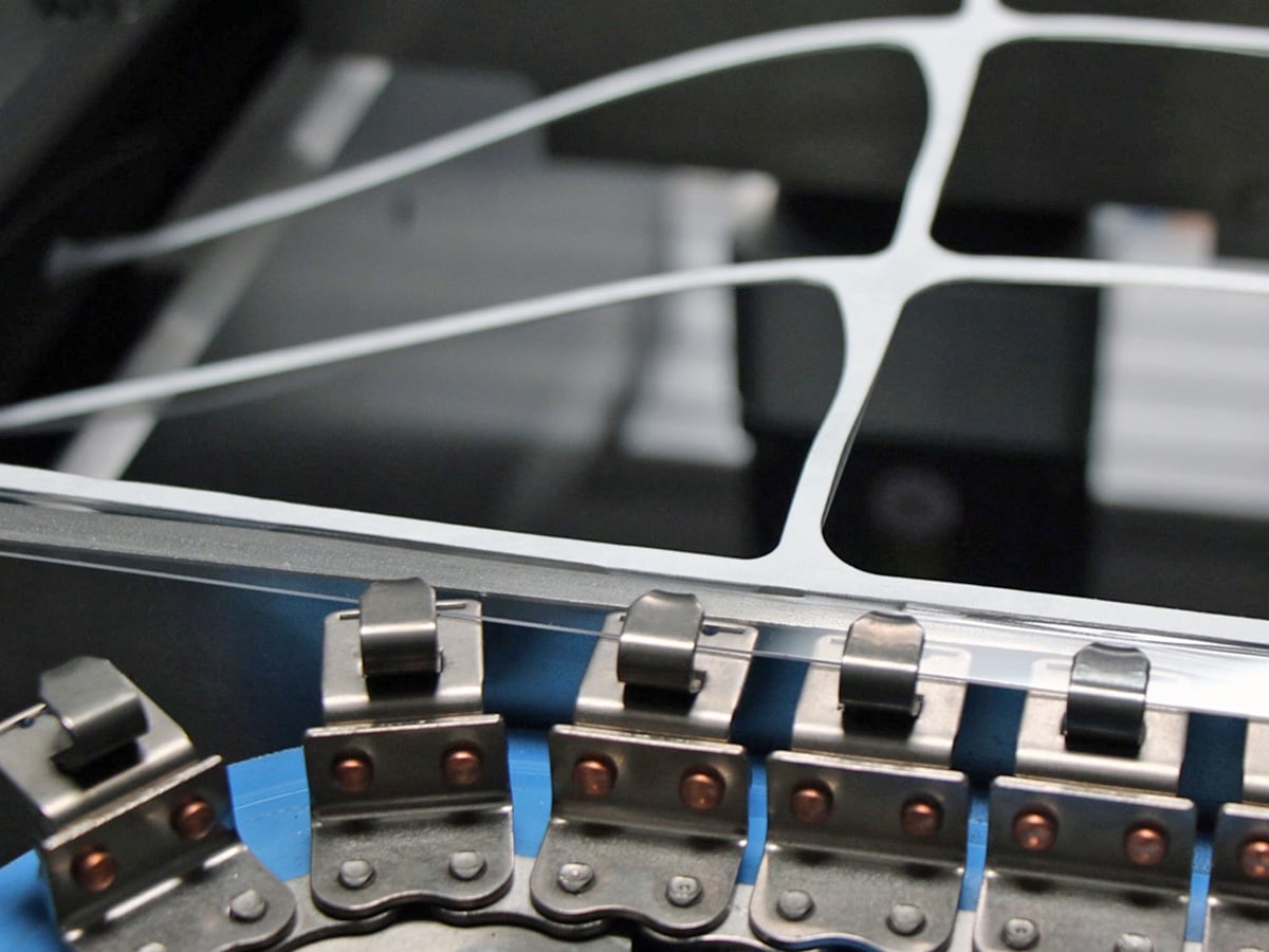 Punching station showing a film web with closely spaced blister cavities leaving minimal waste grid (