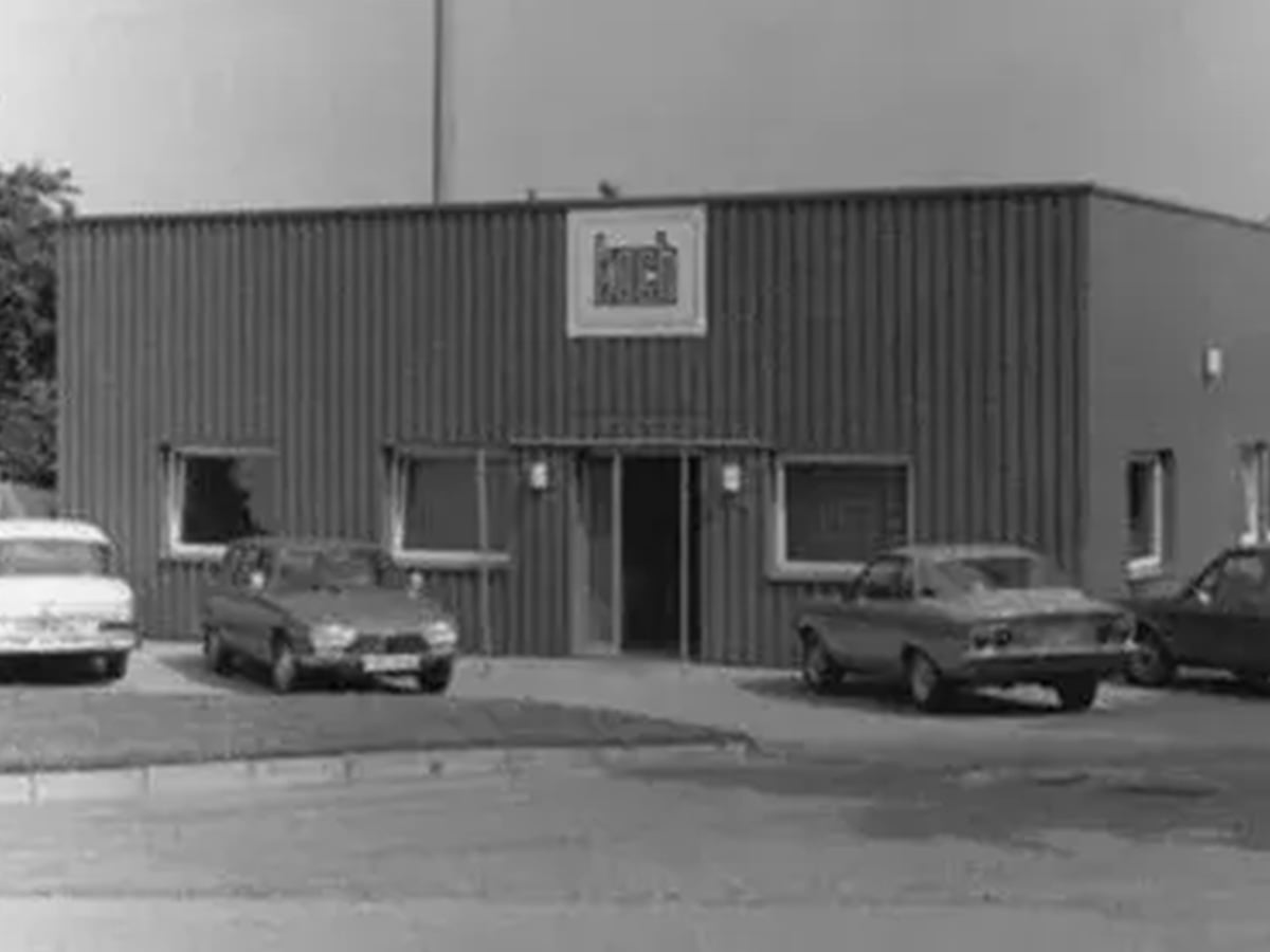 Black-and-white photograph of the first Koch Maschinenbau GmbH building in 1969, with cars parked outside