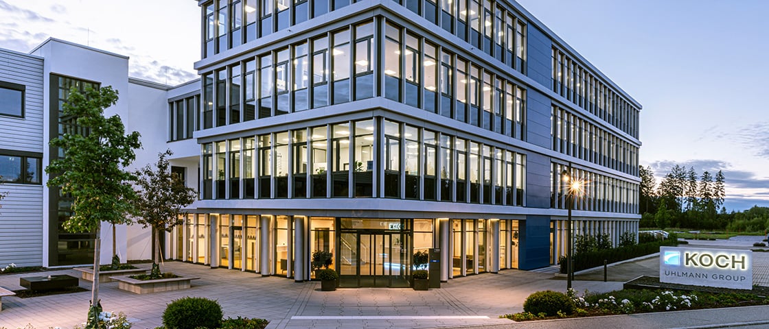 KOCH Pac-Systeme headquarters in Pfalzgrafenweiler at dusk with the illuminated entrance