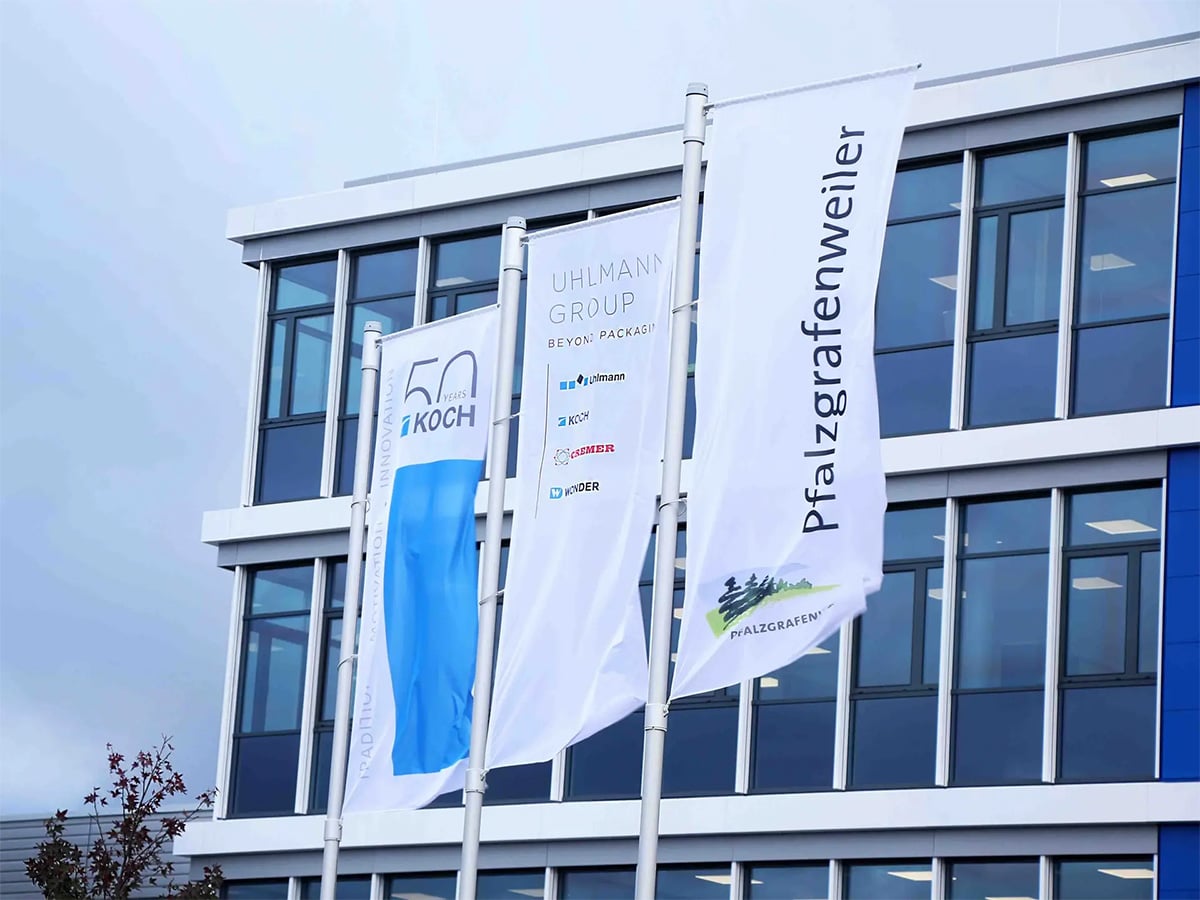 KOCH Pac-Systeme office building in Pfalzgrafenweiler with Uhlmann Group and town flags flying in front, photographed in 2018