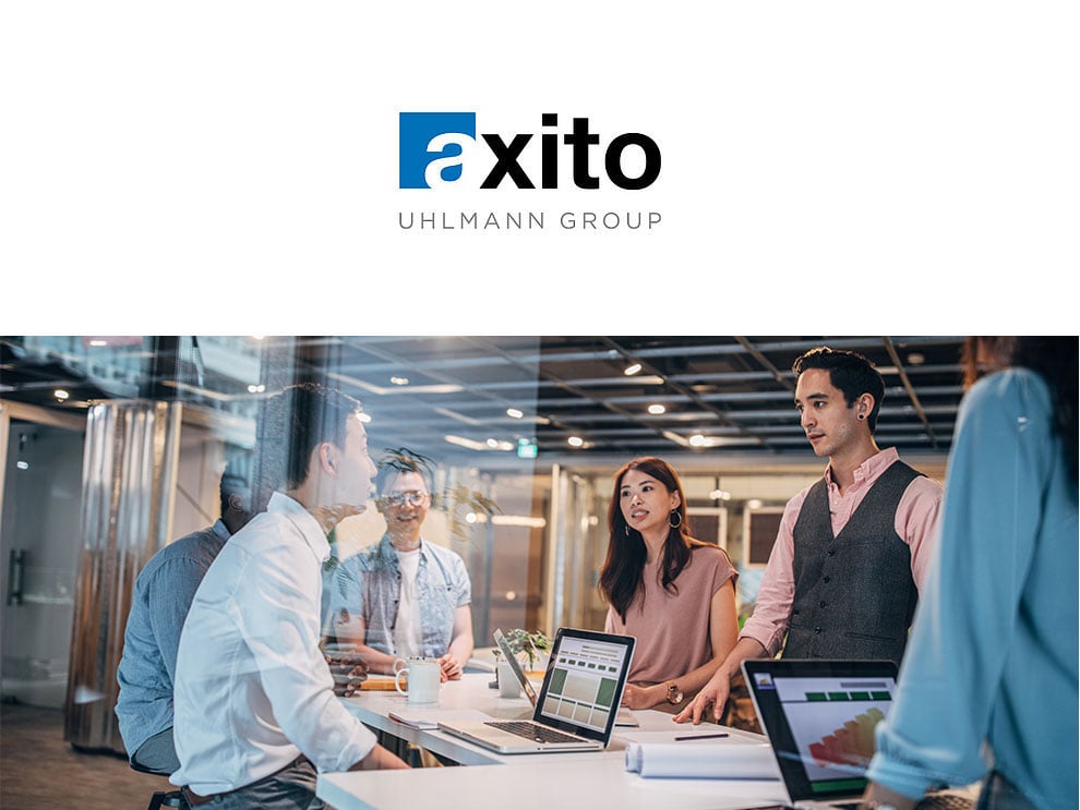 Team meeting at a conference table with laptops, illustrating the shared service activities of Axito, a member of the Uhlmann Group