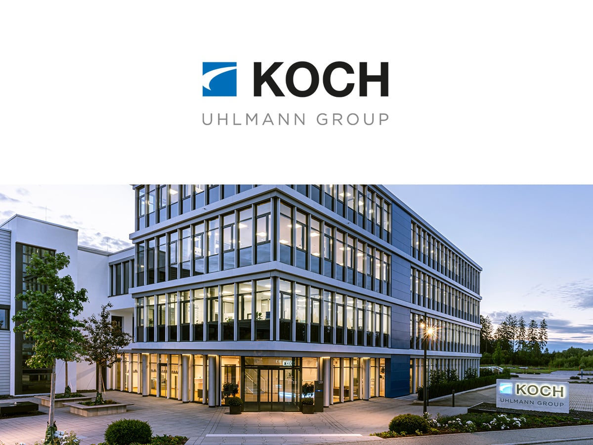 KOCH Pac-Systeme headquarters in Pfalzgrafenweiler at dusk, with illuminated office building and KOCH Uhlmann Group sign