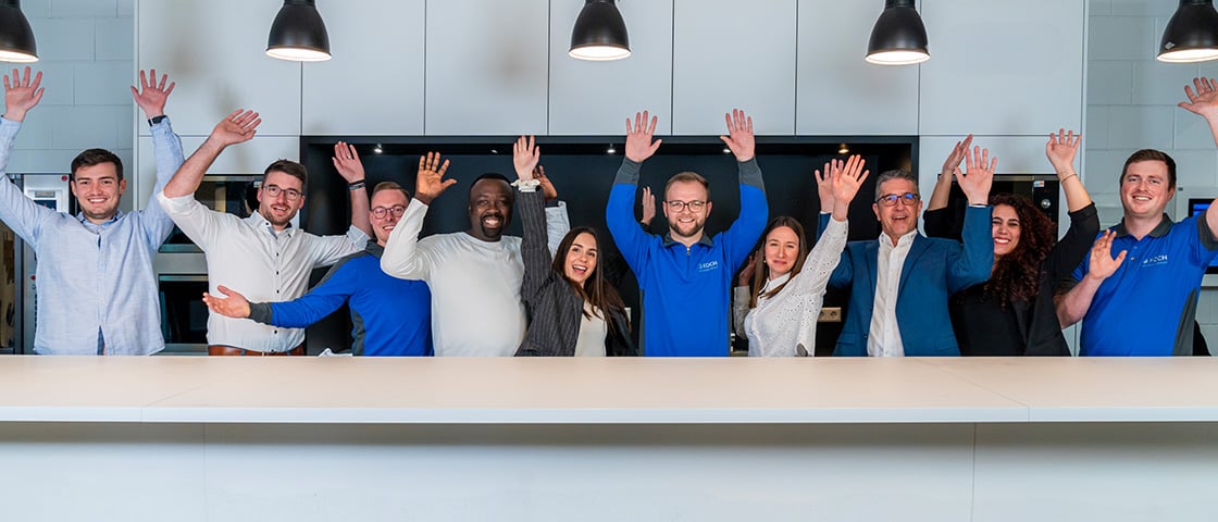Group of KOCH Pac-Systeme employees celebrating together in a modern office environment, representing the company's innovation culture