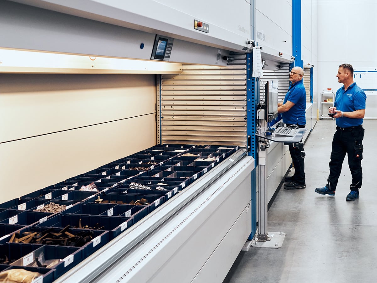 Two employees operating an automated vertical storage system in a warehouse, representing the Warehouse Logistics Specialist apprenticeship at KOCH Pac-Systeme
