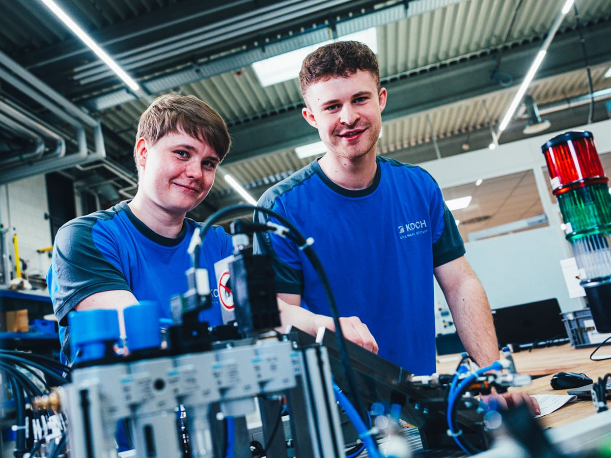 Two KOCH apprentices working together on a mechatronic system in a production environment, representing the Mechatronics Technician apprenticeship