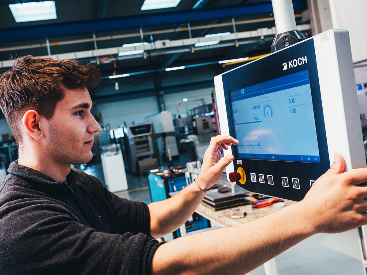 Dual study student operating a KOCH packaging machine touchscreen control panel in a production environment