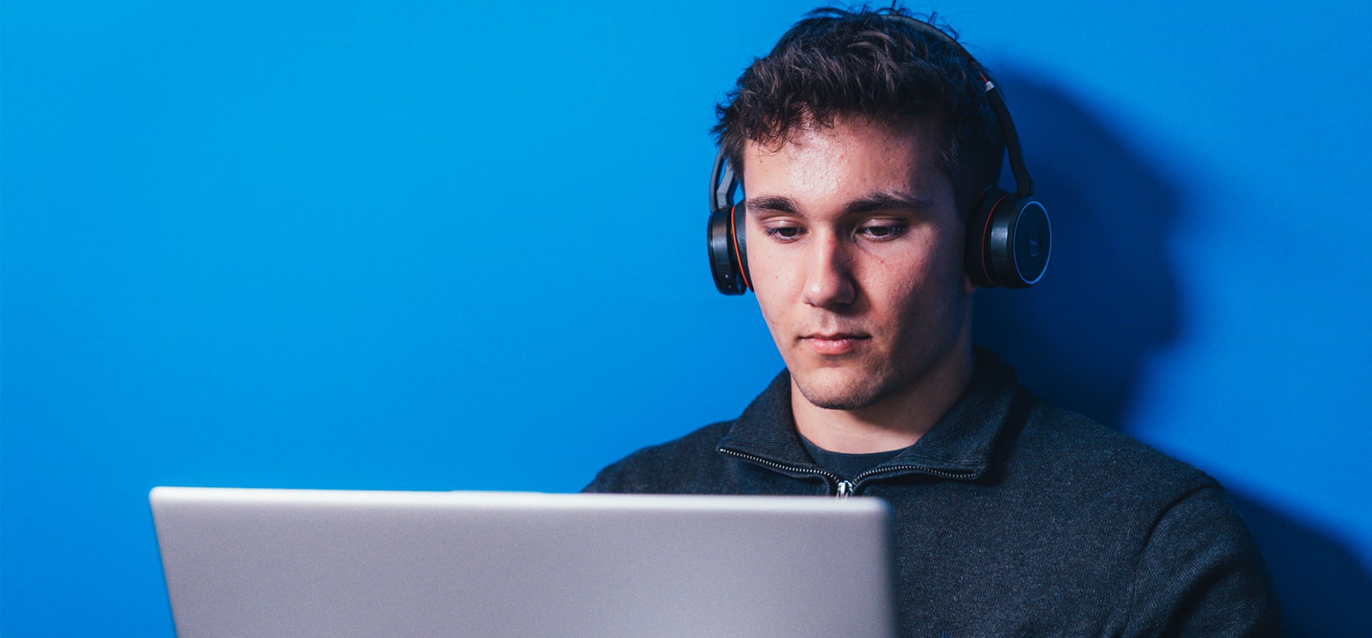 Young man with headphones studying on a laptop, representing the dual study programme at KOCH Pac-Systeme