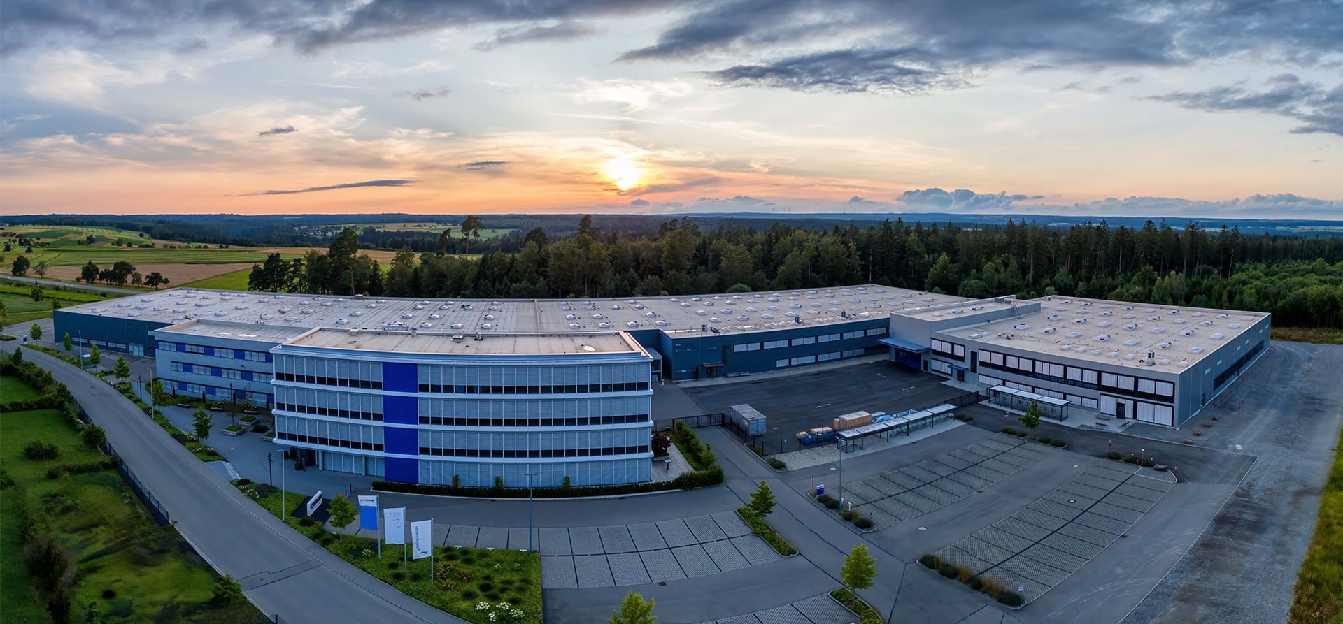 Aerial view of the KOCH Pac-Systeme headquarters in Pfalzgrafenweiler at sunset, surrounded by the Black Forest landscape